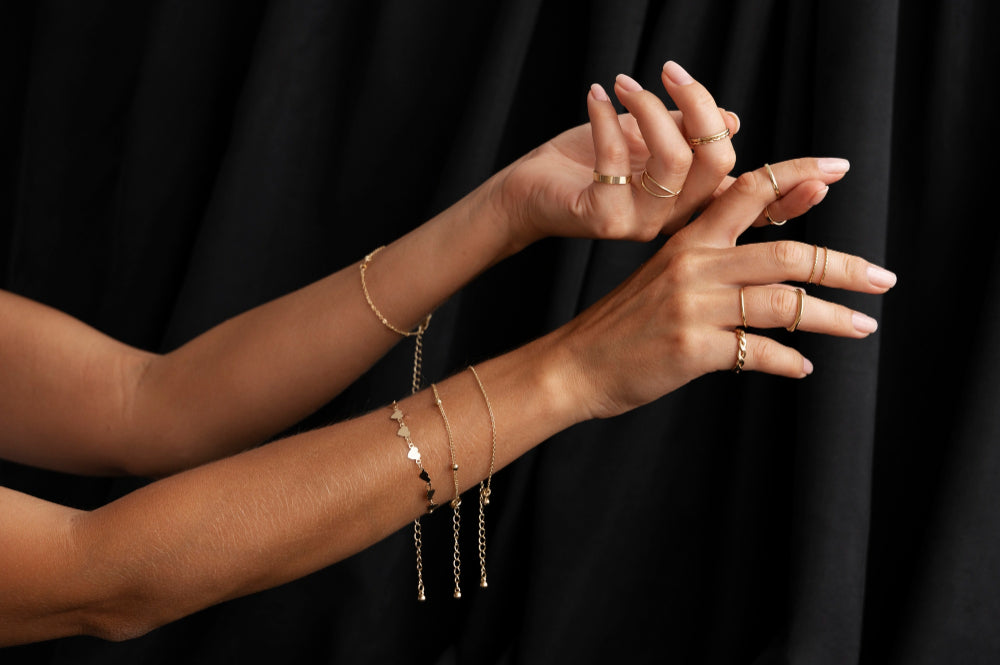 Manos de mujer con varios anillos en sus dedos y pulseras en sus muñecas